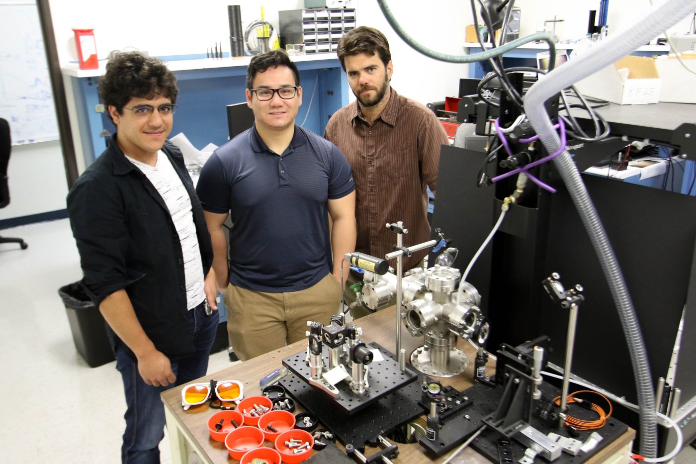 three men standing in a scientific lab