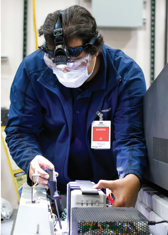 An employee wearing a blue jacket examines a piece of equipment.