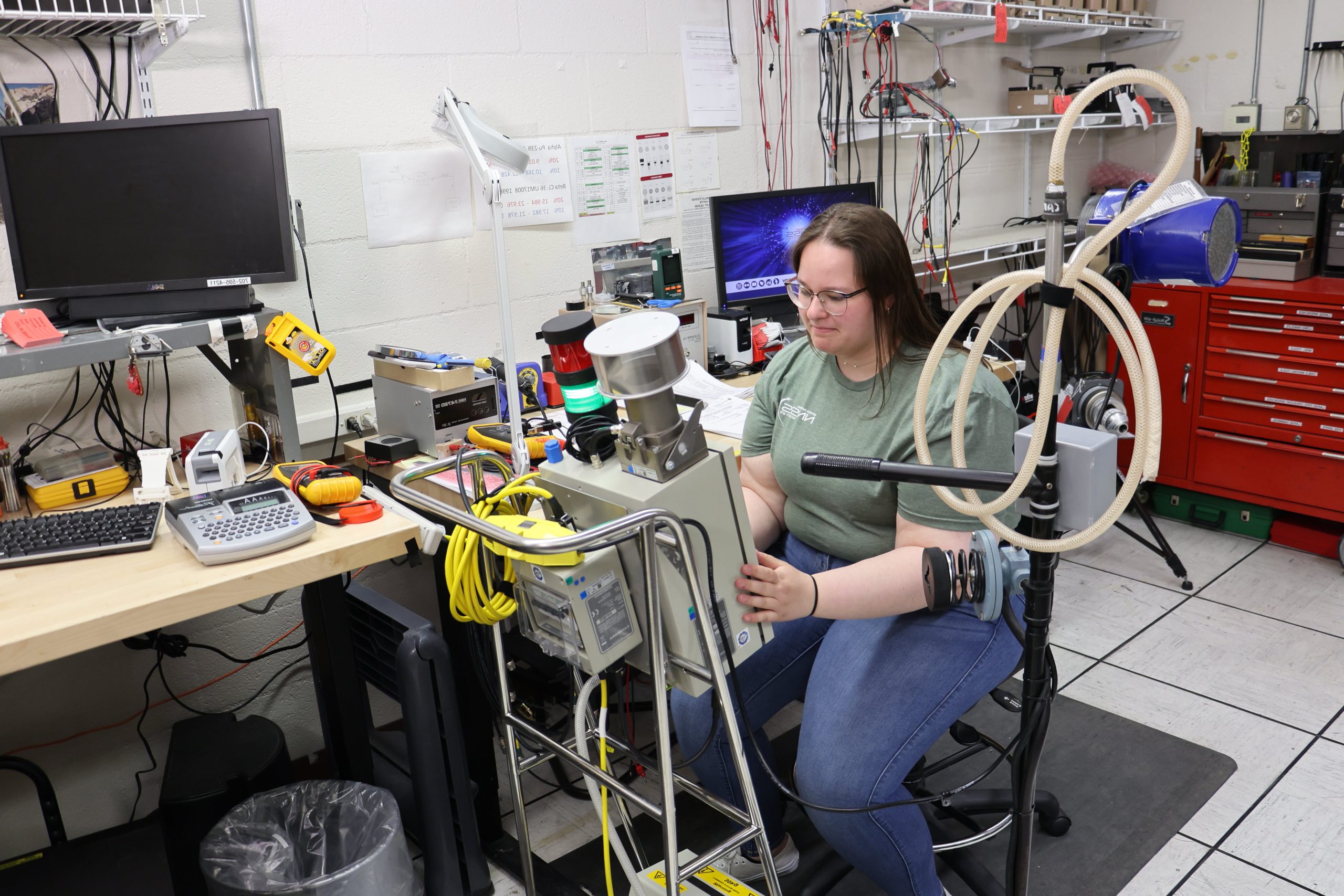 female student intern in green shirt working on machinery in a laboratory