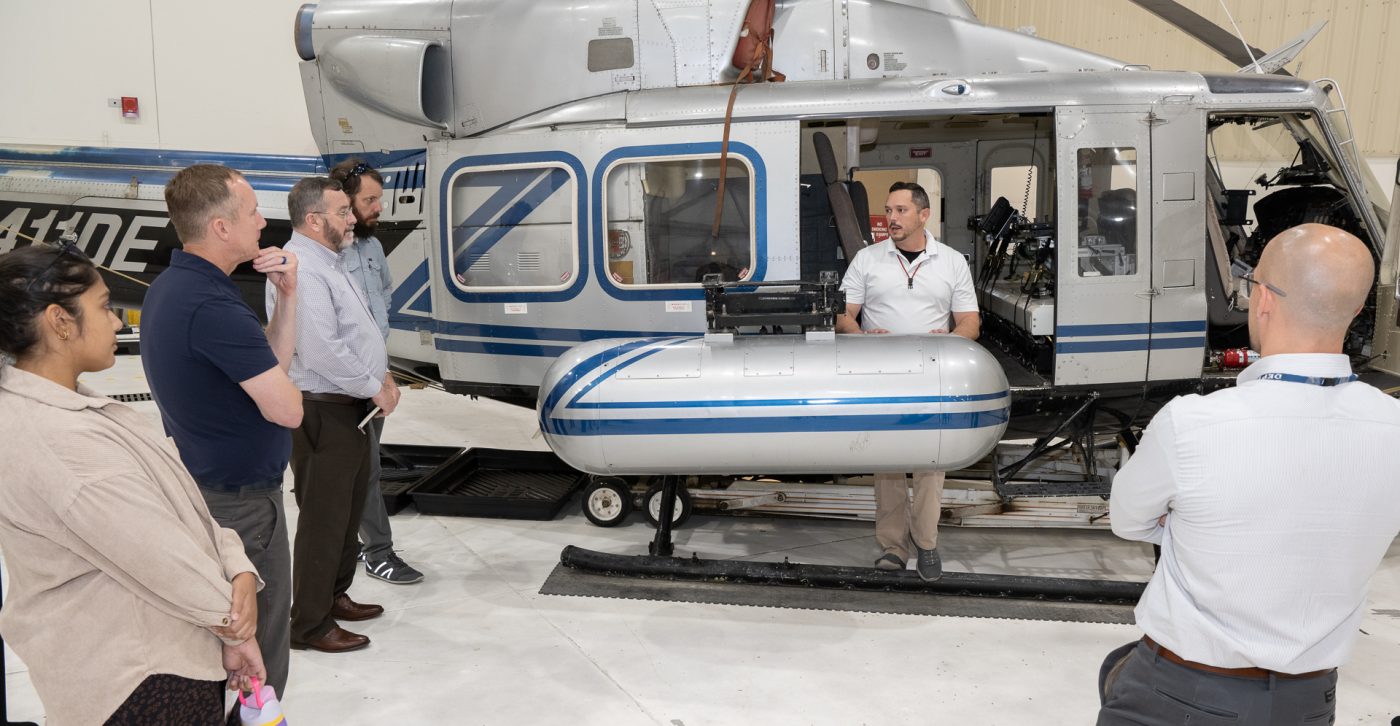 A Nevada National Security pilot gives a group briefing in front of a helicopter.