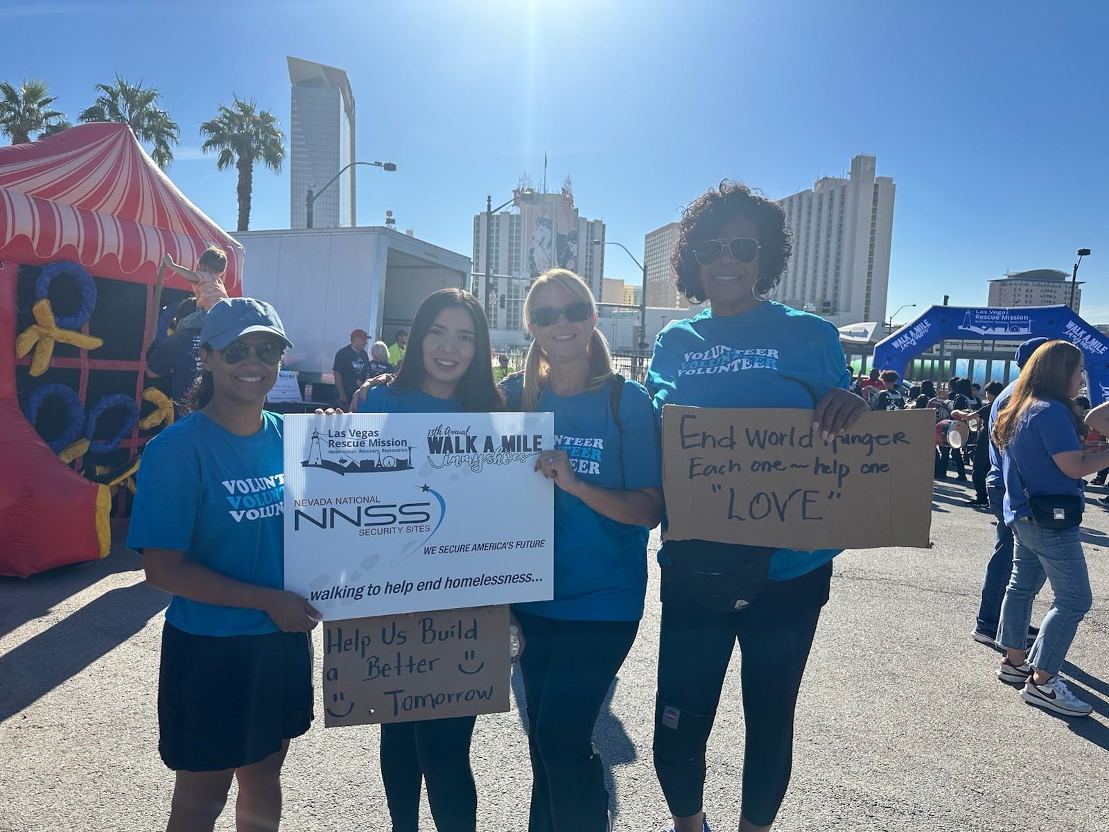 Four NNSS employees hold signs in support of the Walk a Mile in My Shoes campaign.