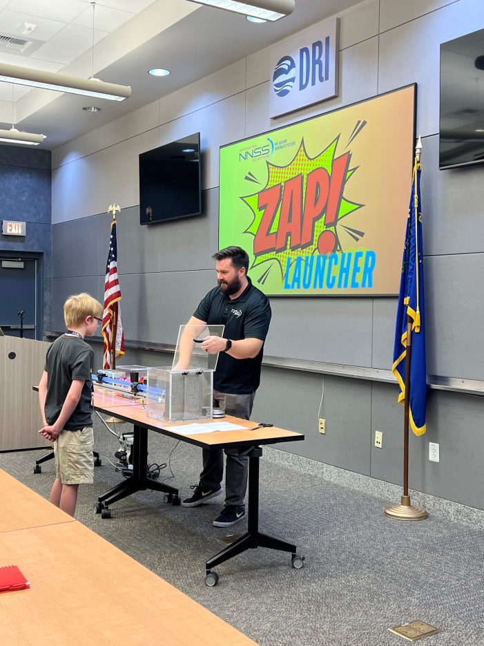 A presenter prepares to launch an object toward a target as part of a science experiment.