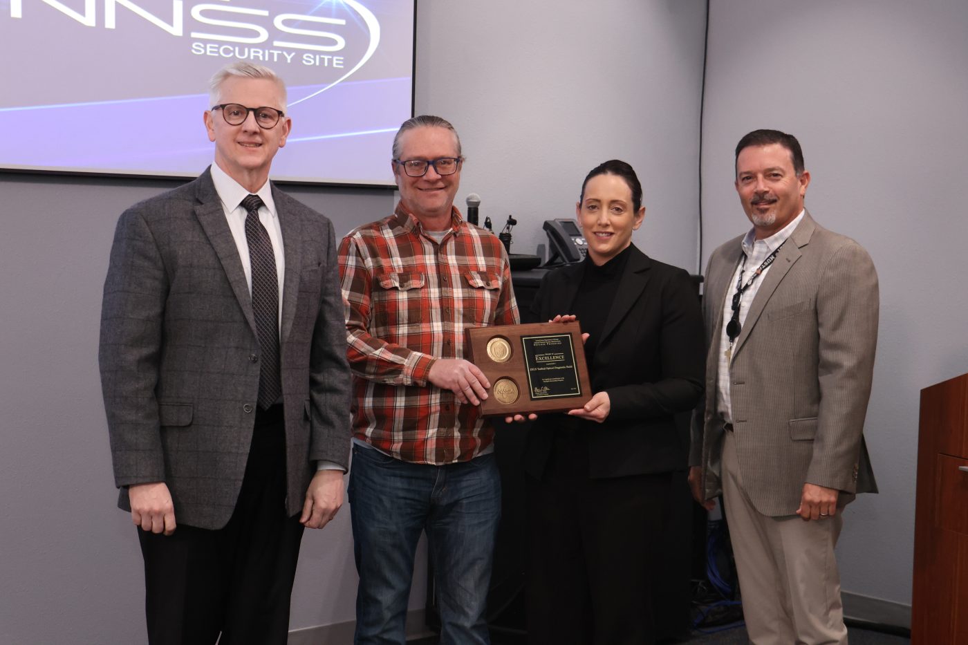 Three men and a woman posed with an award