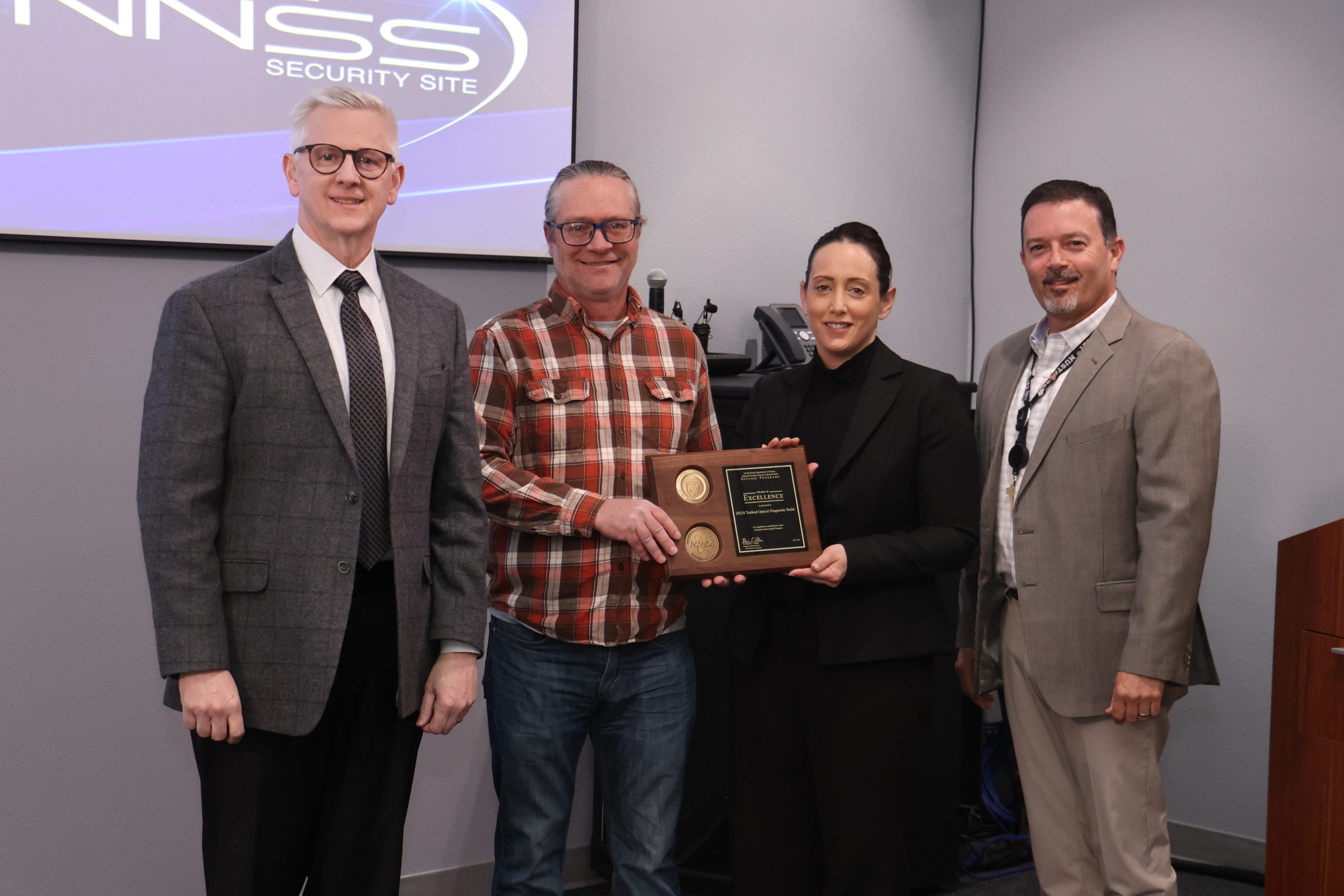 Three men and a woman posed with an award