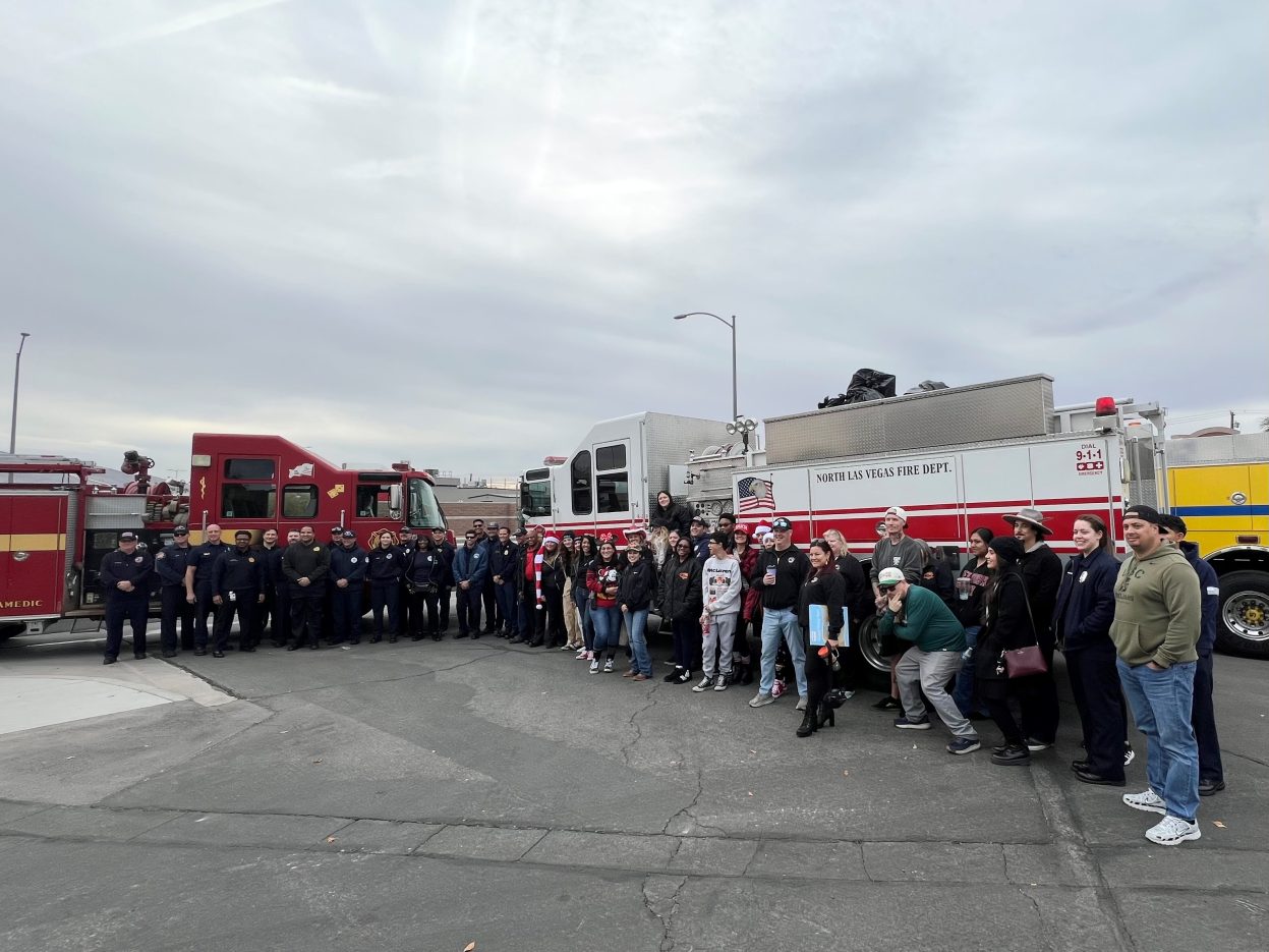 Dozens of Fire & Rescue personnel stand in front of fire engines.