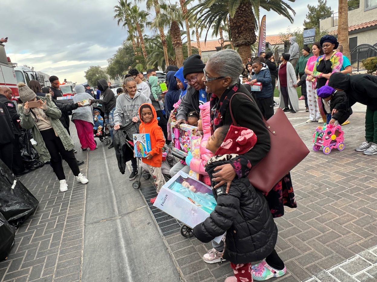 Children smile with gifts at a neighborhood toy distribution.