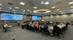 Several dozen employees take part in a presentation in a large conference room.