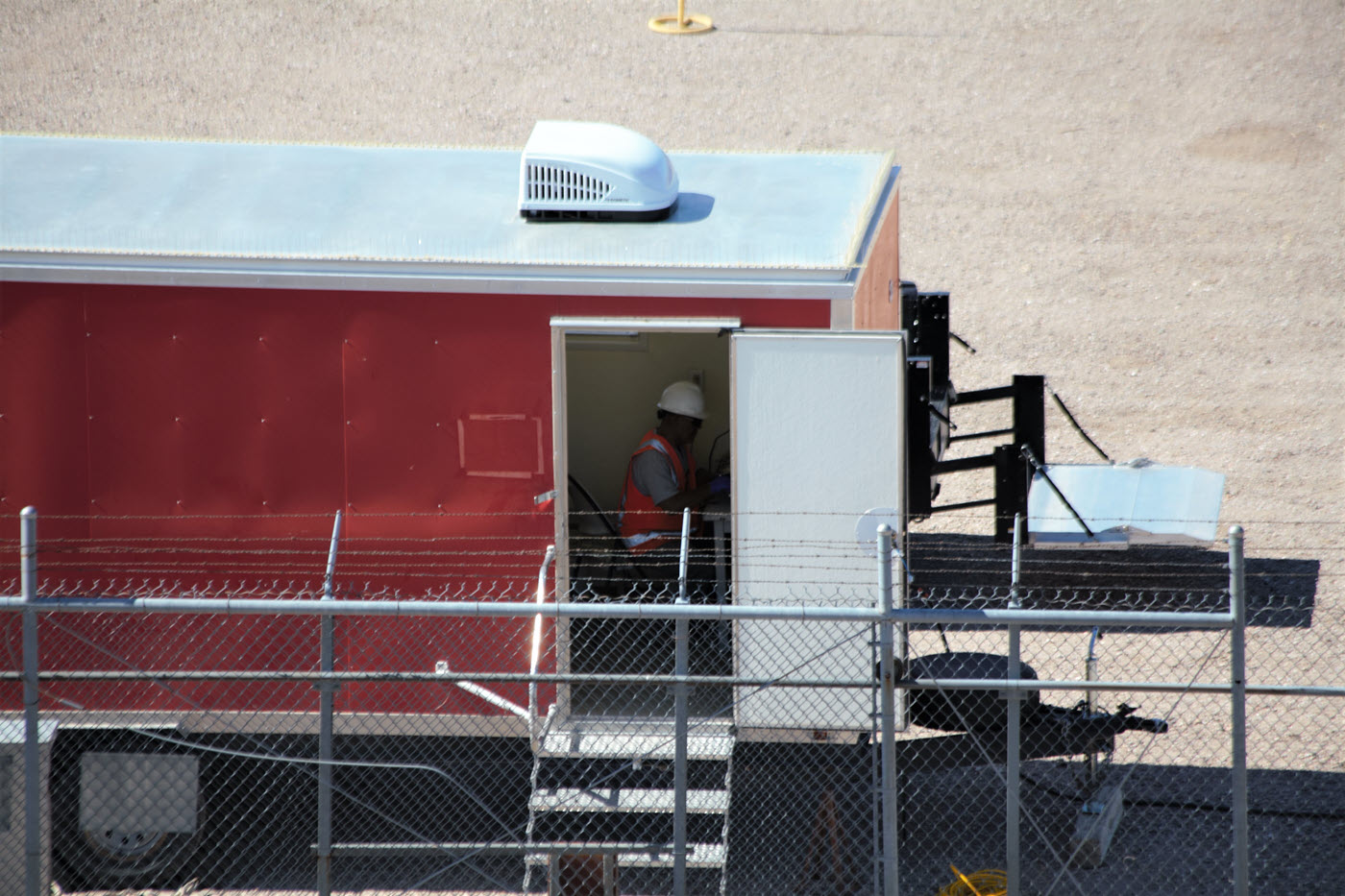 man in hard hat and orange vest inside a red and white trailer