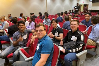 students sitting in auditorium, smiling for the camera