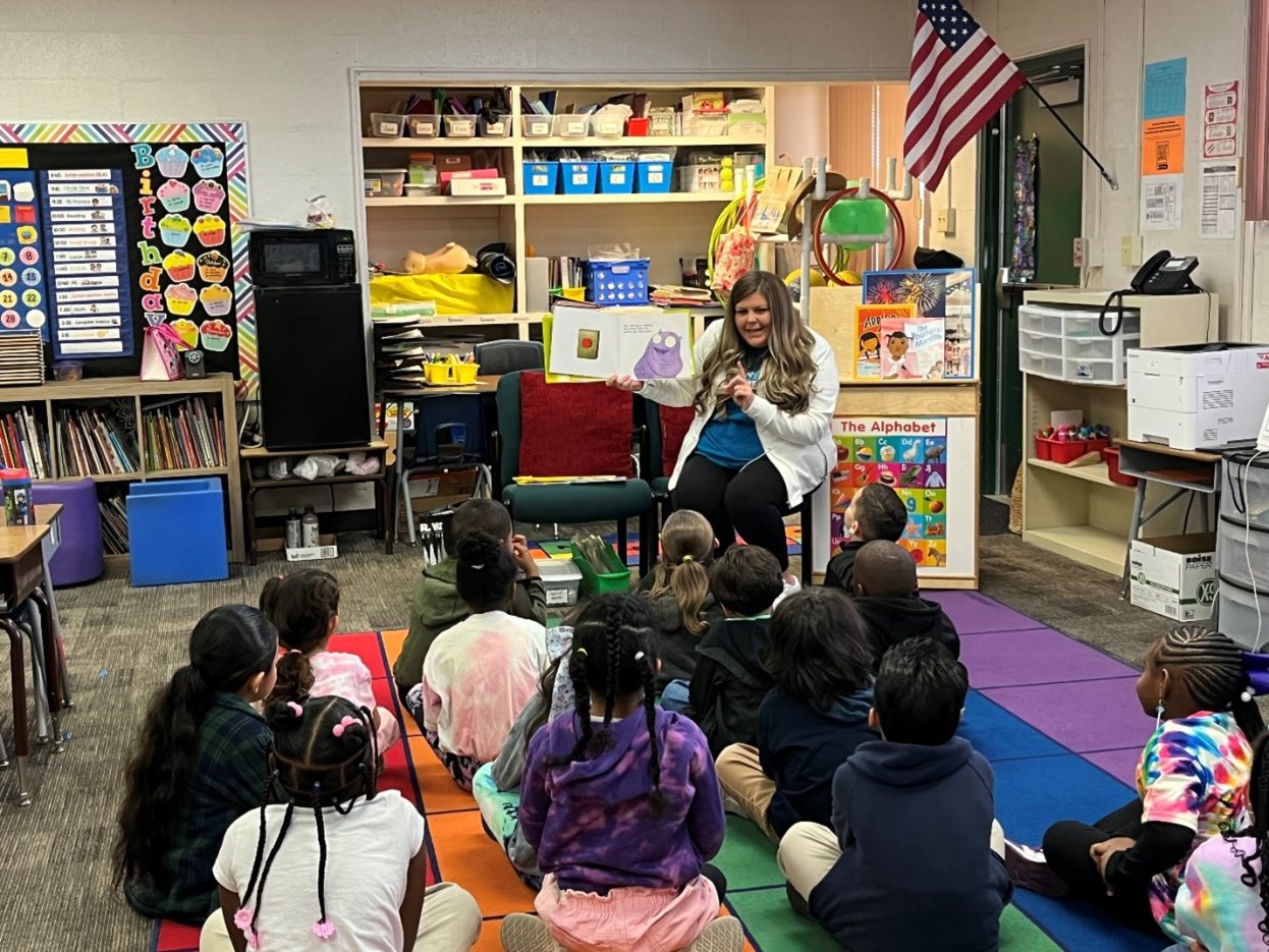 A NNSS volunteer shows book illustrations to a classroom of elementary students.