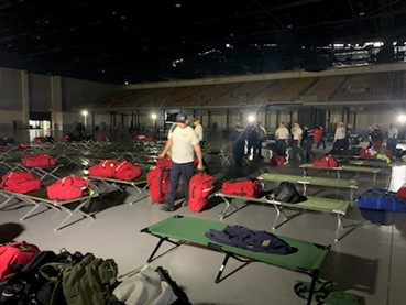 Task force members in a hall with cots. 