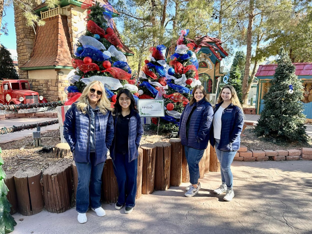 Four NNSS employees stand in front of patriotic-themed trees.