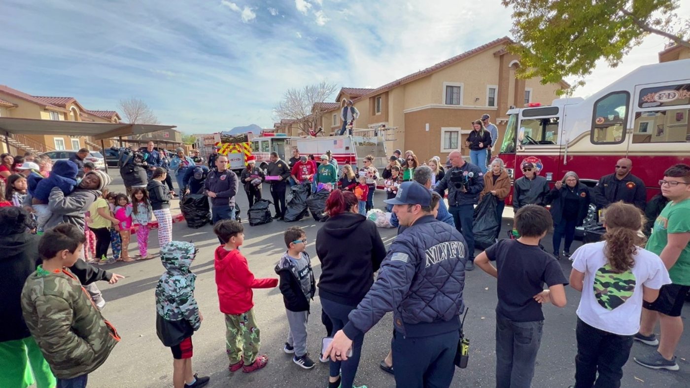 Dozens of children line up in their neighborhood to receive a holiday toy from firefighters.