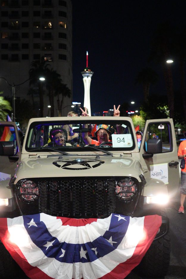 Two employees smile inside a Jeep decorated with patriotic colors.