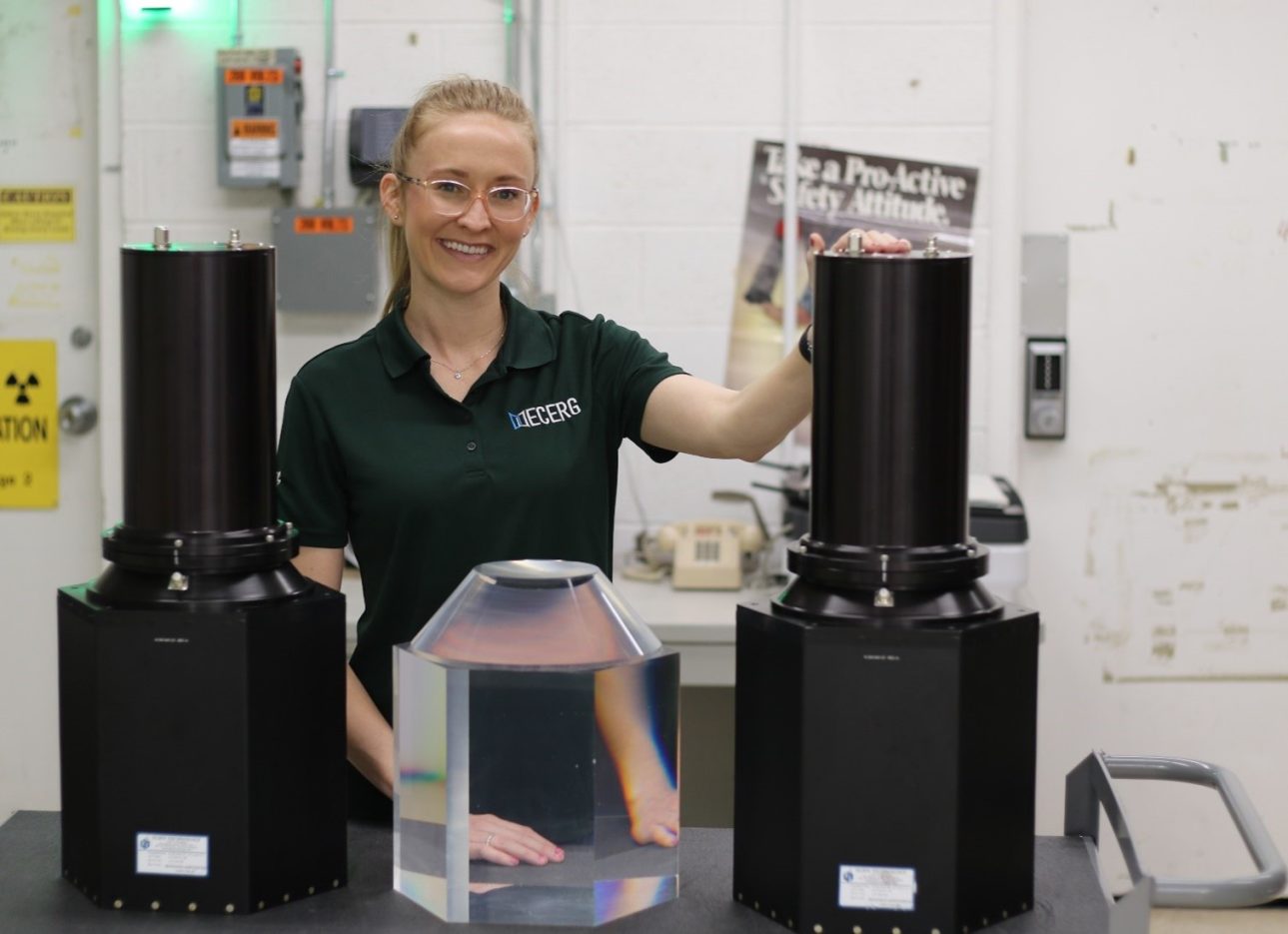 A woman stands with materials that are part of the NNSS' Multi-Layered Avalanche Diamond detector research.