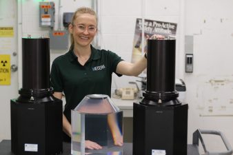 A woman stands with materials that are part of the NNSS' Multi-Layered Avalanche Diamond detector research.