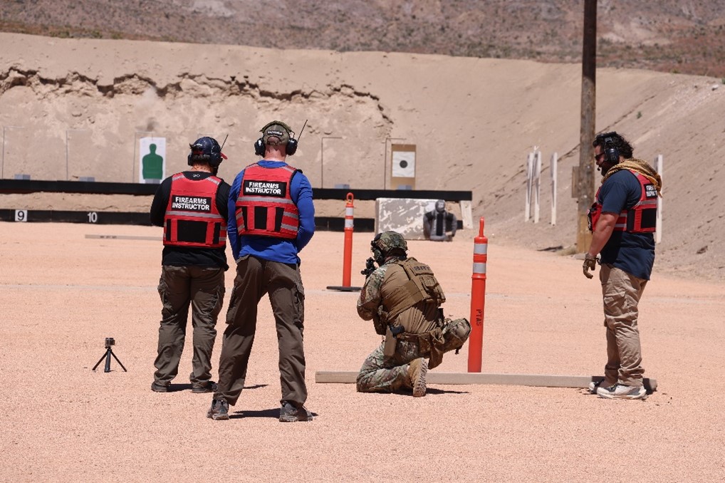 Three firearms instructors wearing red vests work with a member of the NNSS Protective Force.