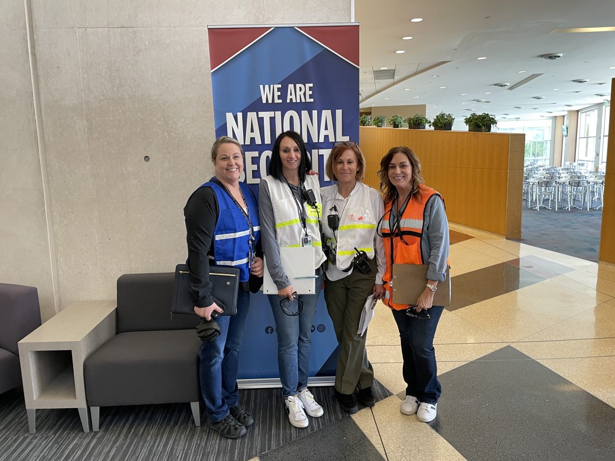 Image of four NNSS employees standing in front of the cafeteria.