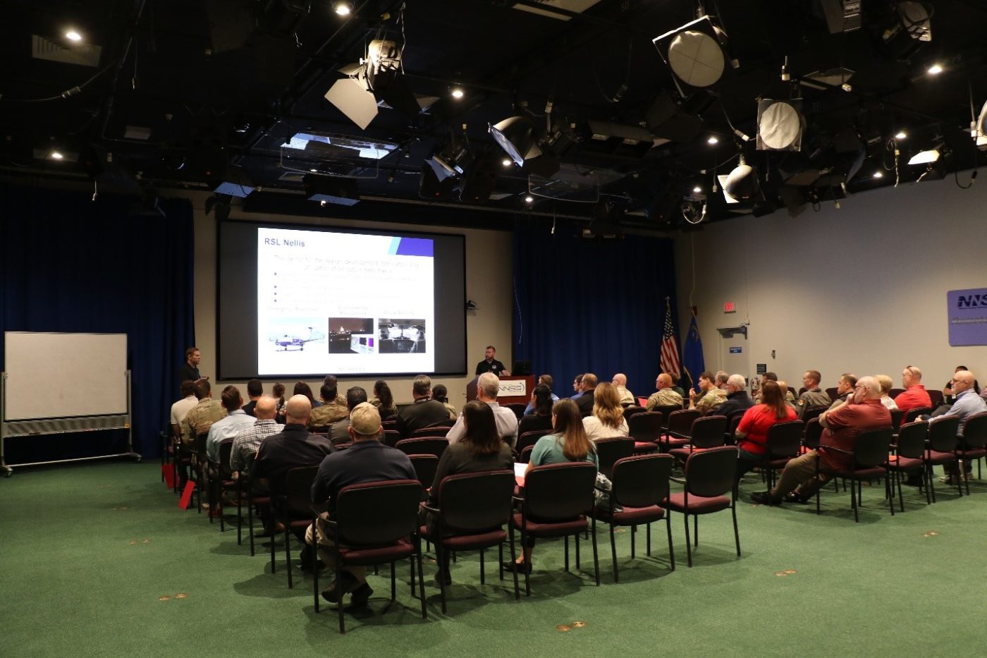 A group faces a presentation screen inside an auditorium. 