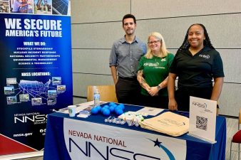 three employees standing behind a table at a career fair