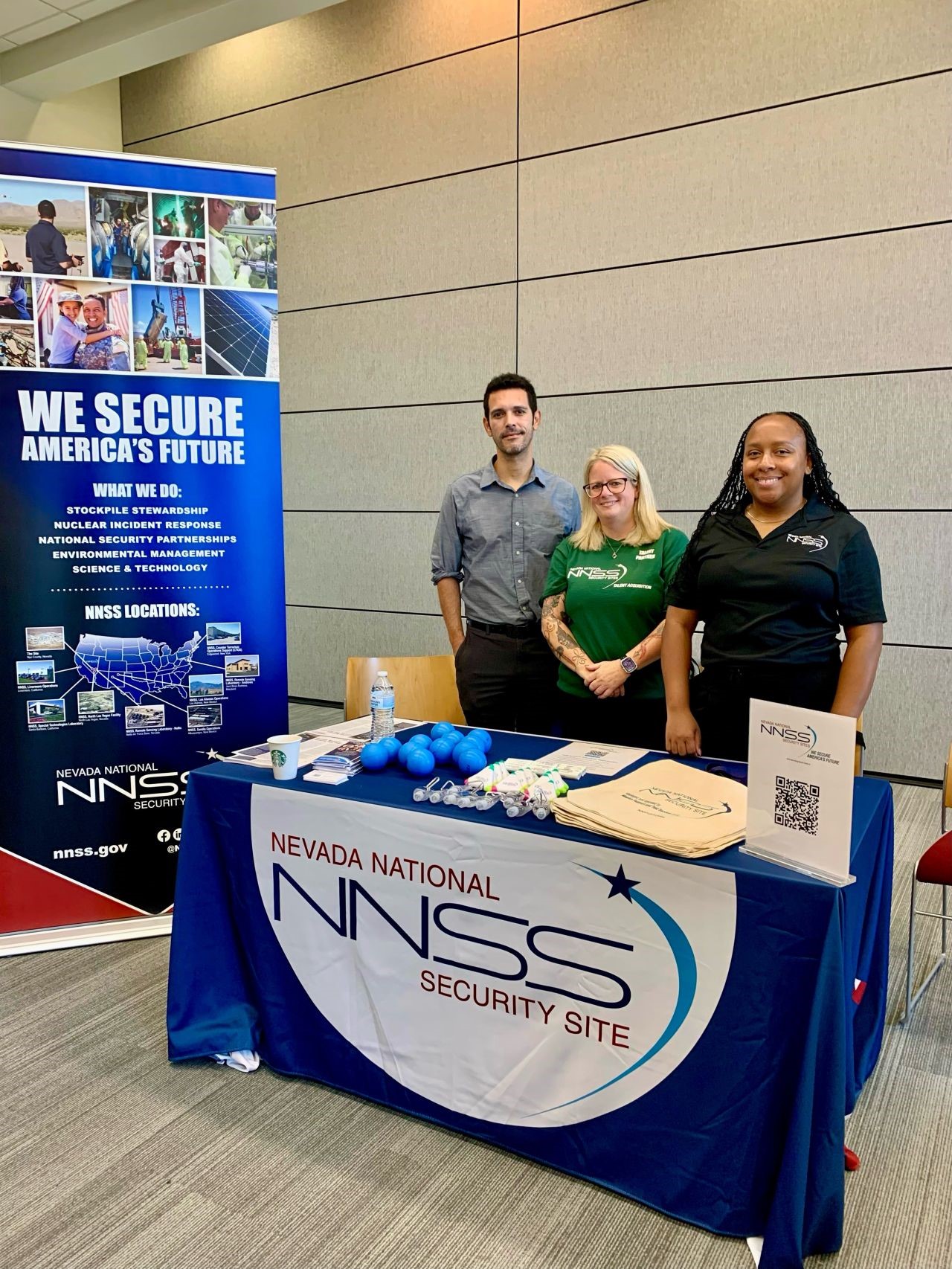 three employees standing behind a table at a career fair