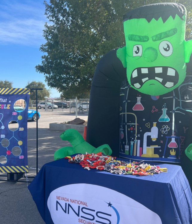 A Halloween-themed inflatable character pictured behind a table with candy.