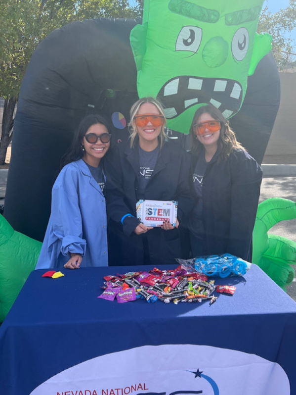 Three women stand with Halloween-themed decorations.